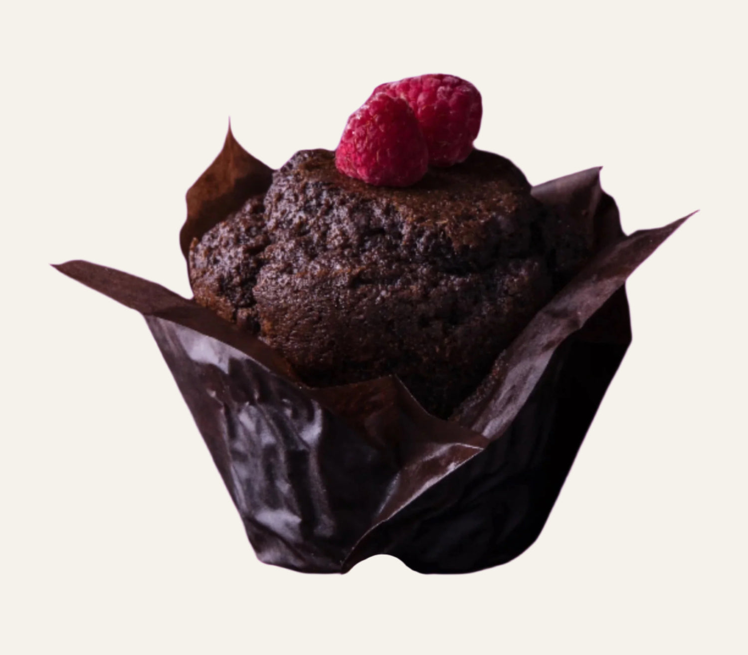 Chocolate muffin with a raspberry on a dark surface with chocolate bars and nuts.